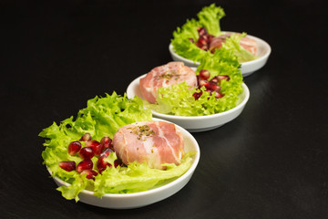goat cheese with bacon on a frisee lettuce leaf with pomegranate as garnishing