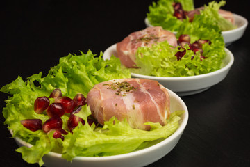 goat cheese with bacon on a frisee lettuce leaf with pomegranate as garnishing