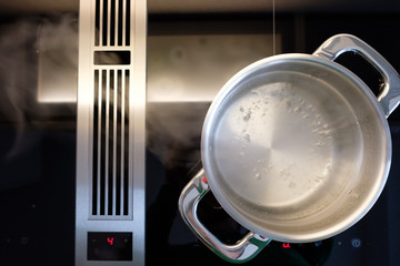 Wasser kocht im Kochtopf und Dampf zieht in Dunstabzug