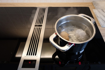 Kochtopf mit kochenden Wasser und Eier auf Induktionsherd