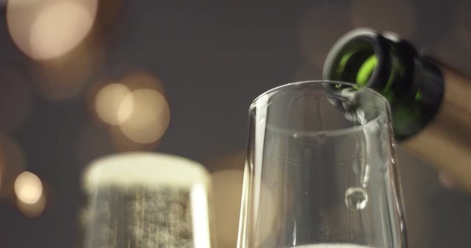 Close up video of pouring sparkling wine into a flute glass on gray backround with blurred lights