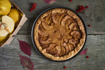 Homemade apple quince pie with fresh fruits on rustic wooden background. Top view