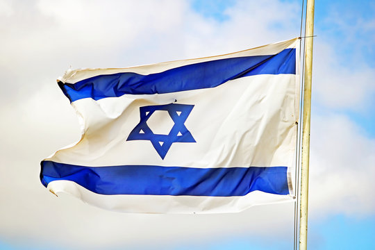 Israel flag close up shot on a background of blue sky. White and blue colors. Israel flag waving against sky