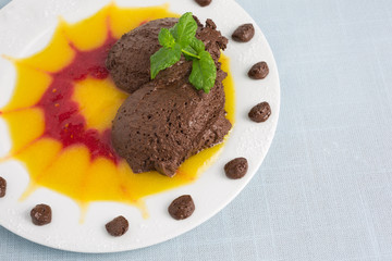 chocolate mousse on plate with pureed fruit in red and yellow