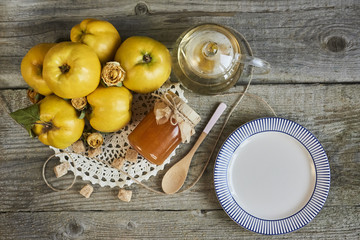 empty plate with jar of jam and quinces on rustic wooden background