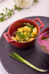 Potatoes with greens, are served in a chugunka with a feather of green onions