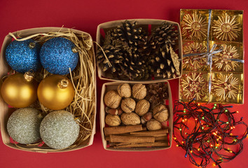 Christmas decorations, pine cones and nuts in boxes on red backround