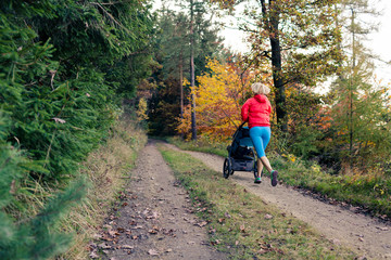 Obraz premium Running mother with stroller enjoying motherhood at autumn sunset
