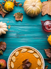 Autumn fall still life background on dark green wooden table. Pumpkins, leaves, traditional thanksgiving pumpkin pie