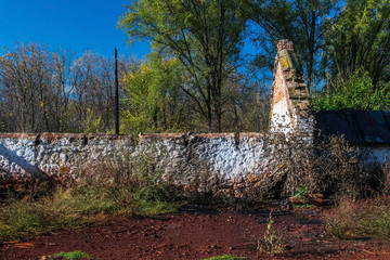 A long wall of an old abandoned ruined brick house in thickets. The debris of an old building. Ukraine