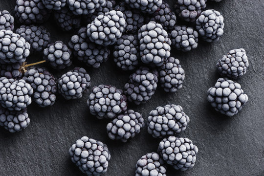 Frozen blackberry on black slate. Close up. Top view. High resolution product.
