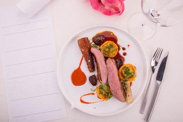 The farmer duck with the glazed carrots, dates, is served with pelmeni from a duck liver in the Red Wine sauce with duck hearts