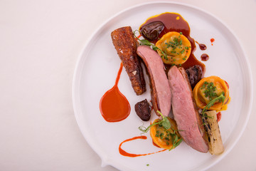 The stewed farmer duck glazed by carrots is served with pelmeni from a liver in the Red Wine sauce