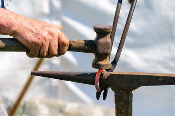 Obraz premium A blacksmith hammers into shape a red-hot iron ring on an anvil