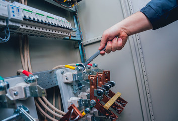 Electricians hands testing switches in electric box. Electrical panel with fuses and contactors