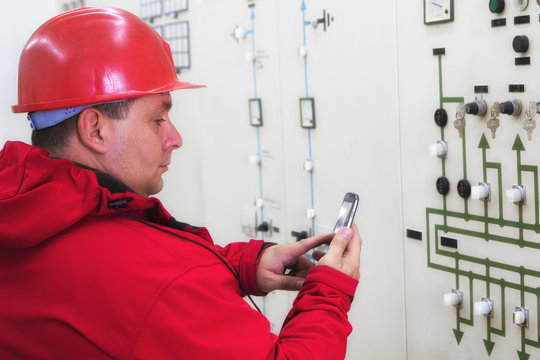 Electrician reading instruments and sending  sms  in power plant control center
