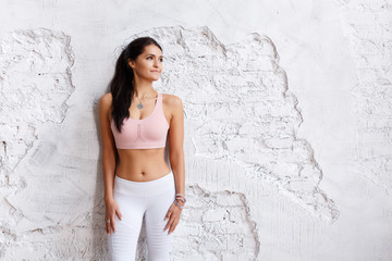Bodybilduing and sport concept. Young fit pretty woman dressed in sport clothes, going to have fitness course with trainer, poses against white brick wall
