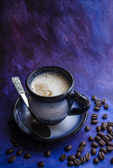 A cup of coffee and coffee beans on a beautiful blue background with space for text.
