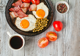 Breakfast, fried eggs with bacon and tomatoes in a frying pan. Menu for a cafe, the concept of the morning.