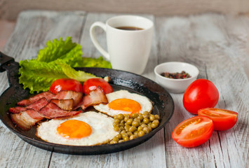 Breakfast, fried eggs with bacon and tomatoes in a frying pan. Morning coffee. Menu for a cafe, the concept of the morning.