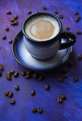 A cup of coffee and coffee beans on a beautiful blue background with space for text.