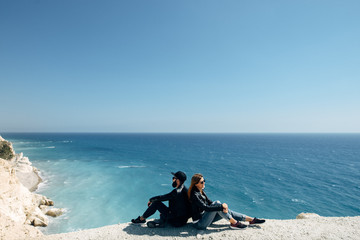Fototapeta na wymiar happy couple in the leather jackets sitting on the beach