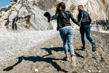 happy couple in the leather jackets running on the beach