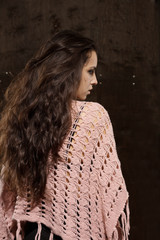 Brunette model with long lush hair in pink sweater on a dark background