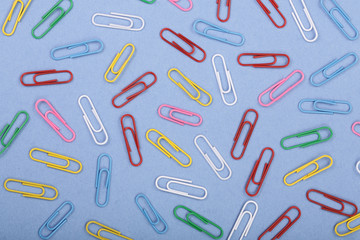 colorful paper clips on blue background. Top view. Flat lay pattern