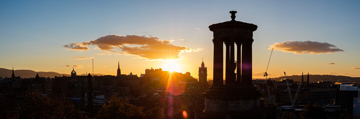Fototapeta na wymiar Summer view of Edinburgh's skyline at unset with the iconic Dugald Stewart Monument in the foreground and the Edinburgh Castle at the back. Scotland, UK