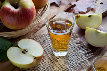 Apple cider vinegar in a glass, with apples in the background