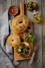 Tapenade, traditional Provence dish with black and green olives, basil and Bagels on old  wooden table background. Selective focus. Top view.