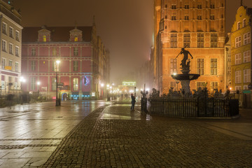 Beautifully illuminated Old Town in Gdansk with fountain of the Neptune. Foggy night. Poland. © vivoo