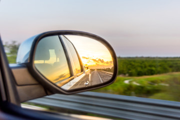 Fototapeta na wymiar Sunset Through Truck Rear View Mirror on the Highway