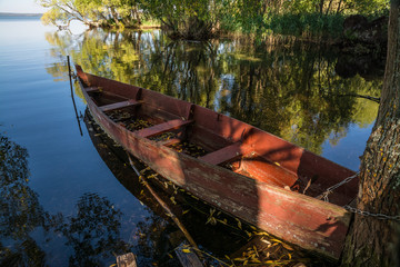 Fototapeta na wymiar Old fishing boat moored in a lake bay