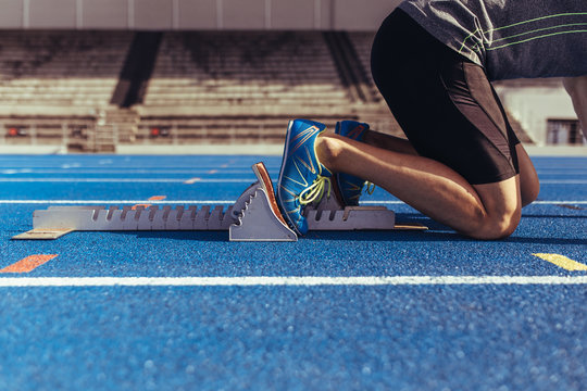 Sprinter resting his feet on starting block on running track