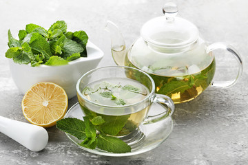 Cup of tea and teapot with mint leafs on wooden table