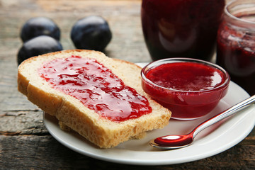 Bread with plum jam on grey wooden table