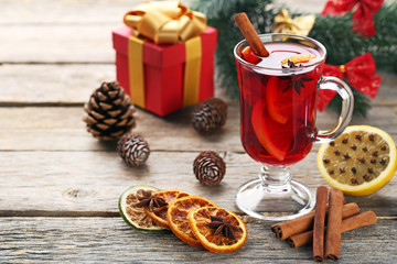 Mulled wine in glass with spices on wooden table