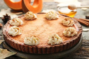Pumpkin tart with whipped cream on wooden table