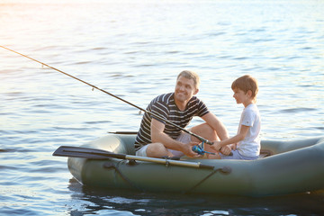 Father with son fishing from boat on river