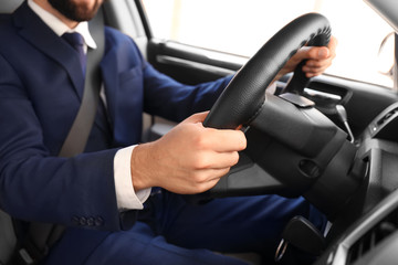 Man in formal suit on driver's seat of car