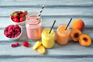 Composition with jars of yummy smoothie on wooden table