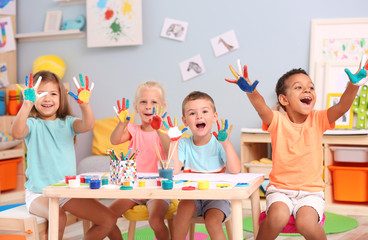 Cute children with painted palms at table indoor