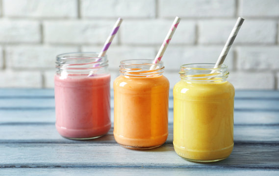 Jars with yummy smoothie on wooden table
