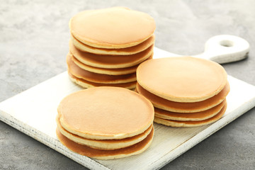Tasty pancakes with cutting board on grey wooden table