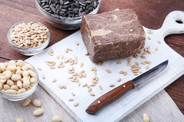 Tasty halva with seeds and knife on cutting board