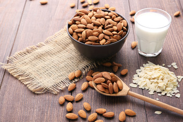 Almonds in bowl with glass of milk on wooden table