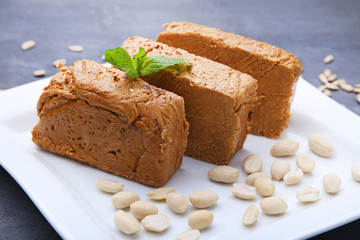 Tasty slices of halva in white plate on grey wooden table