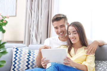 Young couple using tablet computer on sofa at home